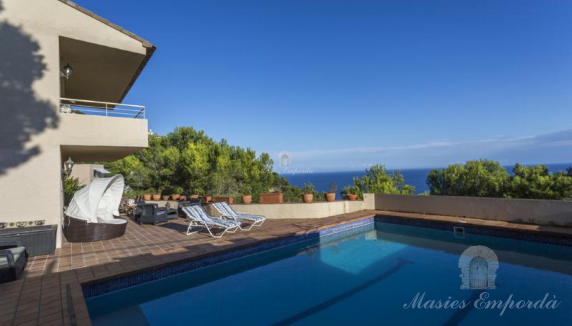 Vistas desde la piscina de parte de la casa, terraza solárium y el mar al fondo de la imagen. 