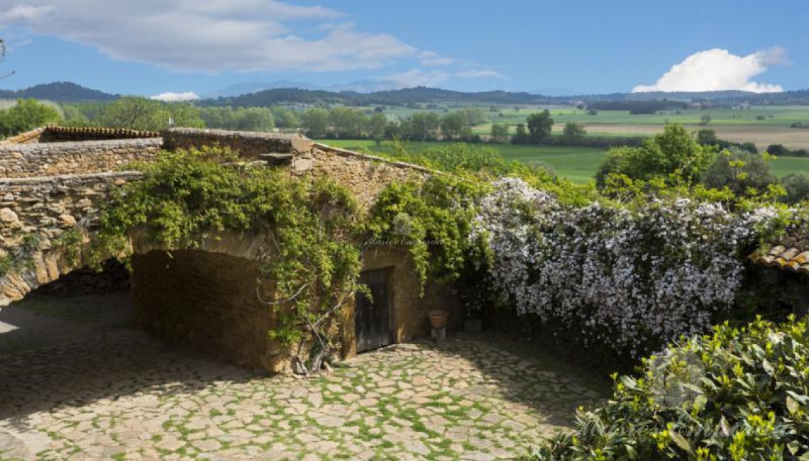  Vista del puente arcado de piedra que soporta terrada desde la perspectiva inversa a la entrada a la masía con espectaculares vistas a los campos de la propiedad y del Baix Empordà 