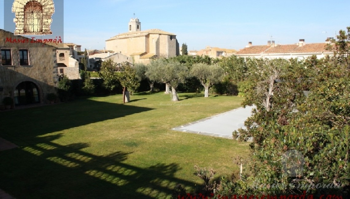 Vista del jardín y la piscina donde se aprecia la iglesia del pueblo al fondo de la imagen  