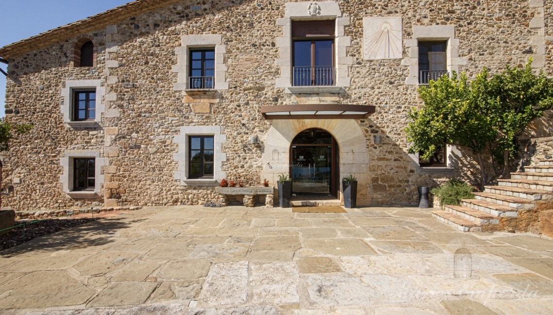 Fachada de la masía con un arco de medio punto en la entrada 