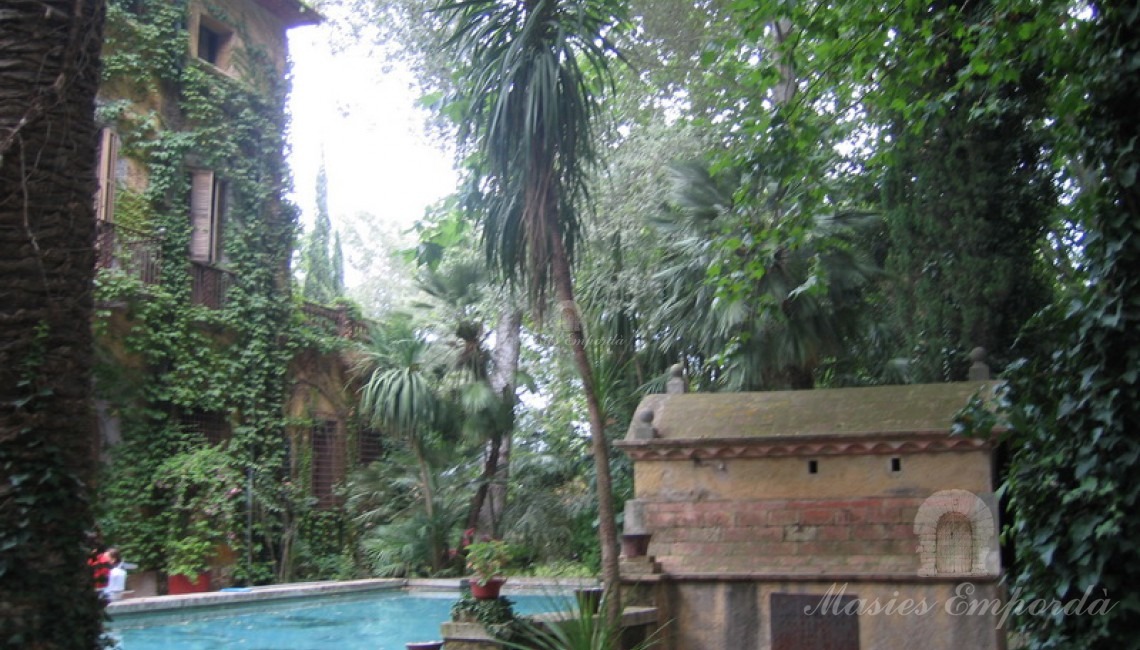 Vista desde el jardín la piscina y la fachada de la casa 