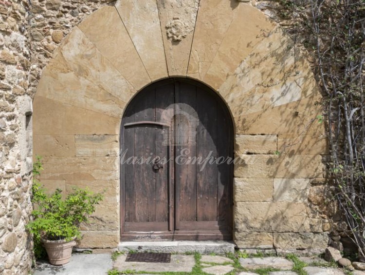 Detalle de la puerta principal de acceso a la masía con este magnífico arco de piedra tallada 