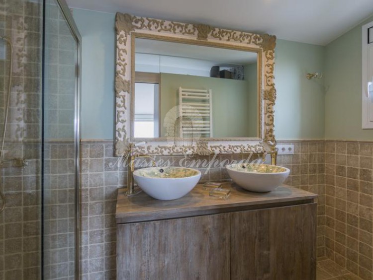 Baño completo con ducha de la suite, con detalle de piedra de travertinos en las paredes.