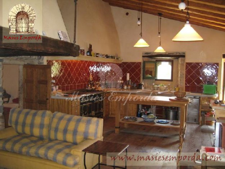 Cocina de la masía con chimenea abierta y salón 
