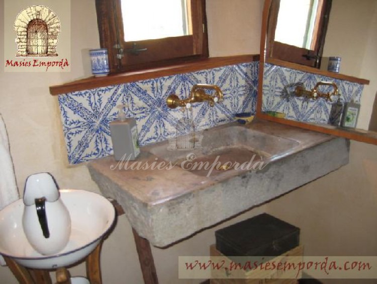  Baño de planta con pica de piedra y azulejos de cenefas azules en fondo blanco