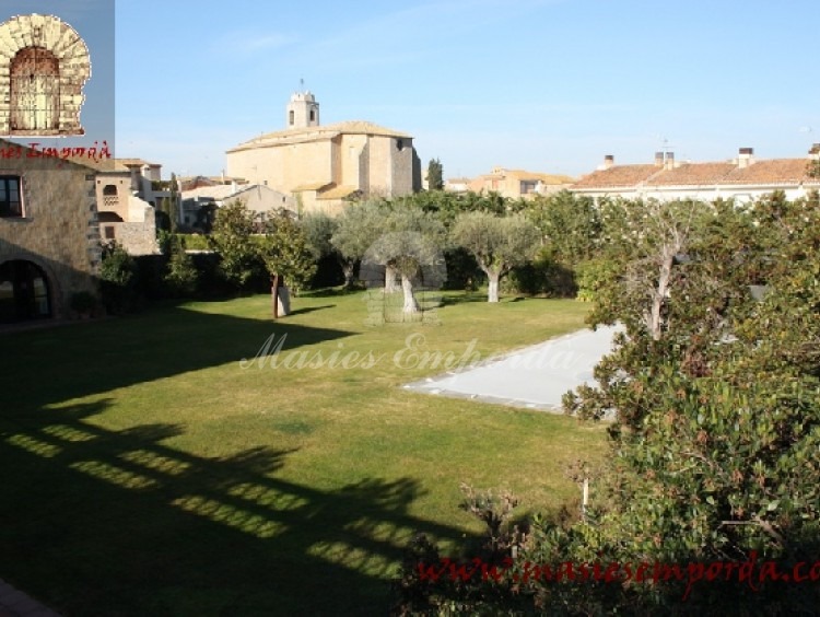 Vista del jardín y la piscina donde se aprecia la iglesia del pueblo al fondo de la imagen  