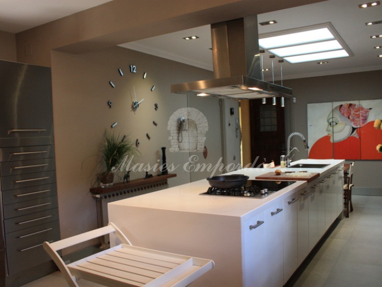 Amplia y luminosa cocina de la casa con isla de trabajo central con el extractor de humos, fogones y fregaderos integrados en ella. 