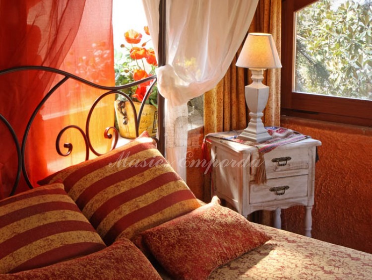 Detalles de la cama con dosel y cabezal en forja con ventanas en arco con vistas al jardín 