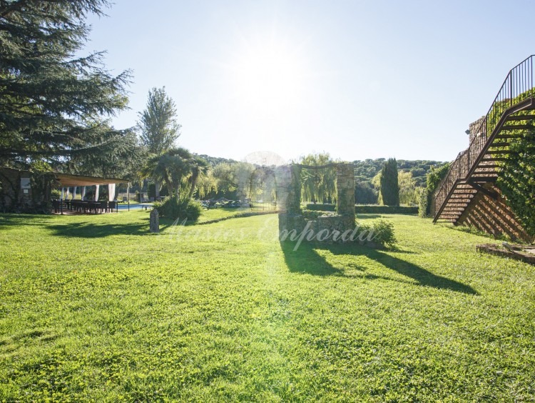 General view of the farmhouse for sale located in the town of Pals in the Baix Empordà and the garden on the inside of this where the vine can be seen covering the structure of the house as a whole.