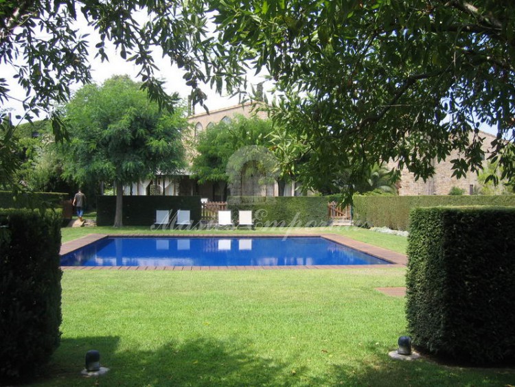 Vista desde el jardín de la piscina y de la casa al fondo de la imagen 