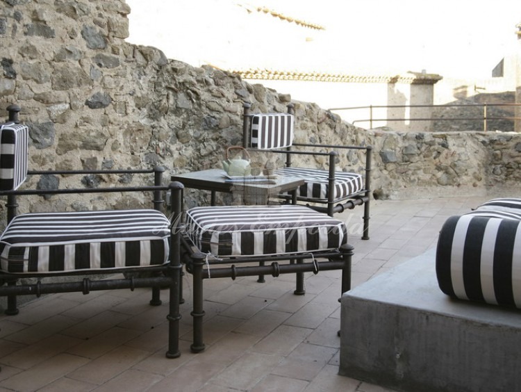 Terraza de la tercera planta de la vivienda con sillones de forja tapizados en tejido a rallas de color negro y blanco. 