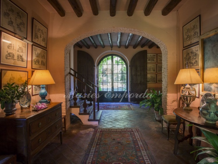 Entrance hall to the house with the access staircase to the floor on one side with central arch for loading and wooden beams seen.