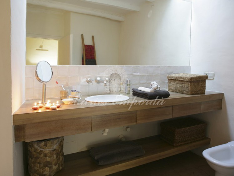 Detalle del baño de la suite con detalles en madera de la encimera del baño con plato de cerámica en blanco